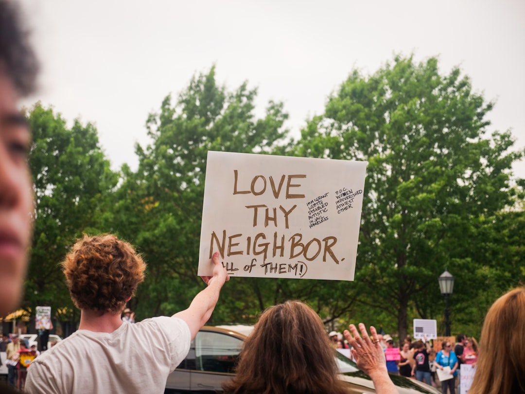 Services-02 Protest sign which reads Love thy neighbor (all of them!)